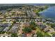 A high angle aerial view shows the home surrounded by mature trees in a residential area by the lake at 1447 Kingfish Ln, Winter Haven, FL 33884