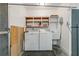 Functional laundry room with washer, dryer, utility sink, and storage shelves at 1447 Kingfish Ln, Winter Haven, FL 33884