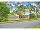 Welcoming 'Orchid Springs' sign surrounded by lush greenery and tall trees against a beautiful sunny sky at 200 El Camino Dr # 206, Winter Haven, FL 33884