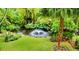 An outdoor view of a pond featuring a fountain with tropical greenery surrounding the area at 200 El Camino Dr # 206, Winter Haven, FL 33884