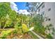 Serene garden view with water feature, lush landscaping, and a beautiful white building in the background at 200 El Camino Dr # 206, Winter Haven, FL 33884