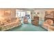 Bright living room featuring floral sofa and chair set, ceiling fan, and blue carpeting at 200 El Camino Dr # 206, Winter Haven, FL 33884