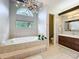 Bright bathroom featuring a soaking tub under a large window and an elegant chandelier at 2204 Kettle Dr, Orlando, FL 32835