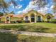 Beautiful yellow home featuring a well-manicured lawn, lush landscaping, and a tile roof at 2204 Kettle Dr, Orlando, FL 32835