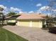 A home featuring a three-car garage with a brick paved driveway, lush landscaping, and tile roof at 2204 Kettle Dr, Orlando, FL 32835