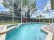 A beautiful screened-in pool surrounded by lush landscaping and a stylish brick deck at 2204 Kettle Dr, Orlando, FL 32835