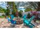 Relaxing backyard with a brick fire pit surrounded by colorful Adirondack chairs and lush tropical landscaping at 315 Bayberry Dr, Polk City, FL 33868