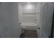 Bathroom with white tiled tub and shower combo, commode and wood-look floors at 3438 Avenue E Nw, Winter Haven, FL 33880