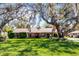 Charming single-story home with a brick chimney, well-manicured landscaping, and mature trees in the front yard at 3614 Twisted Oak Ct, Lake Wales, FL 33898