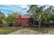 View of a two-story brick house with a lush backyard, mature trees and chain link fencing at 3655 N Scenic Hwy, Lake Wales, FL 33898