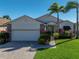 Charming home featuring a brick driveway, well-manicured lawn, and lush landscaping with tropical palm trees at 4115 Muirfield Loop, Lake Wales, FL 33859