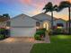 Charming home featuring a brick driveway, well-manicured lawn, and lush landscaping with tropical palm trees at 4115 Muirfield Loop, Lake Wales, FL 33859