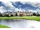 Expansive clubhouse exterior, pond and fountain, with well manicured lawn, shrubbery, and abundant cloudscape at 4115 Muirfield Loop, Lake Wales, FL 33859