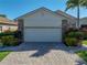 Home featuring an attached two-car garage, stone accents, and well-manicured landscaping at 4115 Muirfield Loop, Lake Wales, FL 33859