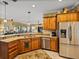 A kitchen featuring wood cabinets, granite countertops, and stainless steel appliances, seamlessly connected to the living area at 4115 Muirfield Loop, Lake Wales, FL 33859
