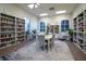 A well-lit library space with bookshelves, a table and chairs, and large windows overlooking the neighborhood at 4115 Muirfield Loop, Lake Wales, FL 33859