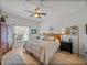 Main bedroom featuring a ceiling fan, light wood floors, a window with sheer curtains, and a king-size bed at 4115 Muirfield Loop, Lake Wales, FL 33859