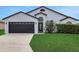 Charming home featuring a well-manicured lawn, dark garage door, and inviting front entrance at 412 Savanna Pointe St, Winter Haven, FL 33884