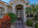 Close up of main entry featuring glass paneled front door, mature landscaping, and stone pathway at 4232 Roebelenii Dr, Lake Wales, FL 33859