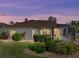 Back exterior of home at dusk, with neutral paint color, manicured shrubs, lawn, and screened-in lanai at 4232 Roebelenii Dr, Lake Wales, FL 33859