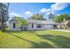 A single-story home boasts a well-kept lawn and mature trees against a bright blue sky at 5115 Woodgreen Ln, Lakeland, FL 33811