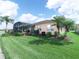 Landscaped backyard with green grass, tropical plants, screened lanai, and beautiful golf course views at 5268 Pebble Beach Blvd, Winter Haven, FL 33884