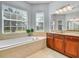 Bright bathroom features a large soaking tub, wood cabinets, and tiled floor at 5268 Pebble Beach Blvd, Winter Haven, FL 33884