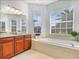 Bright bathroom features a large soaking tub, wood cabinets, and tiled floor at 5268 Pebble Beach Blvd, Winter Haven, FL 33884