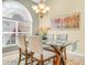 Bright dining area featuring a glass table, upholstered chairs, and a large picture window at 5268 Pebble Beach Blvd, Winter Haven, FL 33884