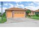 Home exterior featuring a three-car garage, stone accents, and a well-manicured lawn at 5268 Pebble Beach Blvd, Winter Haven, FL 33884