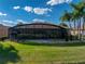 A screened lanai enhances the backyard, surrounded by lush lawn and palm trees at 5357 Hogan Ln, Winter Haven, FL 33884