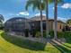 Beautiful backyard with lush lawn, mature palm trees, and a screened lanai at 5357 Hogan Ln, Winter Haven, FL 33884