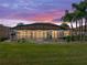 Twilight view of the screened lanai, featuring cozy lighting and a lush lawn at 5357 Hogan Ln, Winter Haven, FL 33884