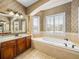 A bathroom featuring a large soaking tub with tile surround and a vanity with dark wood cabinets at 5357 Hogan Ln, Winter Haven, FL 33884