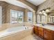 A bathroom featuring a soaking tub under windows and a vanity with dark wood cabinets at 5357 Hogan Ln, Winter Haven, FL 33884
