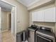 A laundry room featuring modern washer and dryer units and white cabinets at 5357 Hogan Ln, Winter Haven, FL 33884