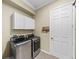 A laundry room featuring modern washer and dryer units, white cabinets, and a door at 5357 Hogan Ln, Winter Haven, FL 33884