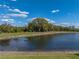 Picturesque view of a pond surrounded by lush greenery and mature trees at 5357 Hogan Ln, Winter Haven, FL 33884