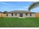 Back exterior showcasing a flat, grassy yard with a sliding glass door entrance at 583 Drayton Rd, Winter Haven, FL 33884