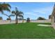 Large backyard with green grass, palm trees, and a white privacy fence at 583 Drayton Rd, Winter Haven, FL 33884