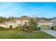 Charming single-story home with well-manicured lawn, lush landscaping, and a welcoming, covered entryway at 7327 Bent Grass Dr, Winter Haven, FL 33884
