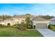 Attractive single-story home with lush landscaping, palm tree, and an attached two-car garage at 7327 Bent Grass Dr, Winter Haven, FL 33884