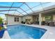 Screened in-ground pool with waterfall feature and covered patio with seating at 7327 Bent Grass Dr, Winter Haven, FL 33884