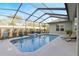 In-ground pool with privacy screen, waterfall feature, and adjacent patio with seating at 7327 Bent Grass Dr, Winter Haven, FL 33884