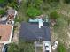 Aerial view of a home with a dark roof, surrounding green trees and vegetation, and a detached garage with white vehicles nearby at 915 Exmoor Way, Lake Wales, FL 33853
