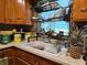 Practical kitchen featuring wooden cabinets, a sink with drying rack, and natural light from the window at 915 Exmoor Way, Lake Wales, FL 33853