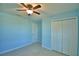 This bedroom features light blue walls, a ceiling fan, closet, and neutral tile floors at 990 Brooke Rd, Fort Meade, FL 33841