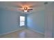 This bedroom features a ceiling fan, light blue walls, a window with blinds, and neutral tile floors at 990 Brooke Rd, Fort Meade, FL 33841