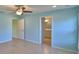 This bedroom features light blue walls, a ceiling fan, tile floors and an attached bathroom at 990 Brooke Rd, Fort Meade, FL 33841