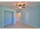 This bedroom features light blue walls, a ceiling fan, closet, and neutral tile floors at 990 Brooke Rd, Fort Meade, FL 33841